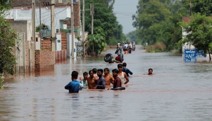 Residents wade through a flooded road, following monsoon rains and rising water levels in Qadirabad village near the Chenab River in Punjab, August 28, 2025. — Reuters