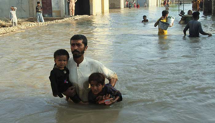 A person carries his children as he wades through a flooded street to catch a rescue boat during evacuations from the flooded area, following monsoon rains and rising water levels of the Chenab River, in Daryapur village, Jalalpur Pirwala, Punjab on September 9, 2025. — Reuters