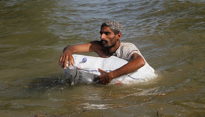 Saleem Ahmed carries a sack of food for his family as he wades through a flooded area, following monsoon rains and rising water levels in the Chenab River, in Basti Khan Bela, on the outskirts of Jalalpur Pirwala, Punjab, September 10, 2025. — Reuters