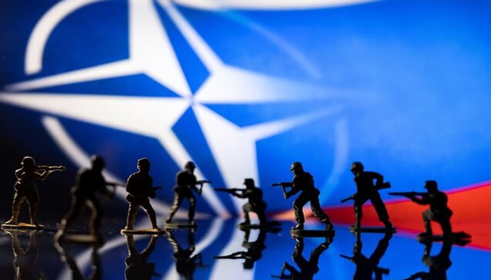 Army soldier figurines are displayed in front of the NATO logo and Russian flag colours background in this illustration taken, February 13, 2022. — Reuters