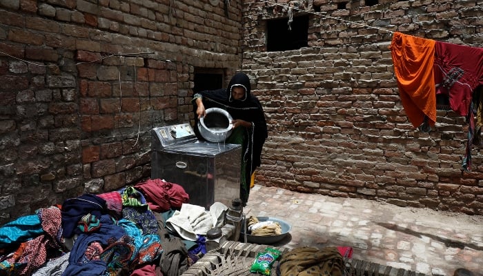 Zahida,16, washes clothes during a heatwave, outside her family home,  May 16, 2022. — Reuters