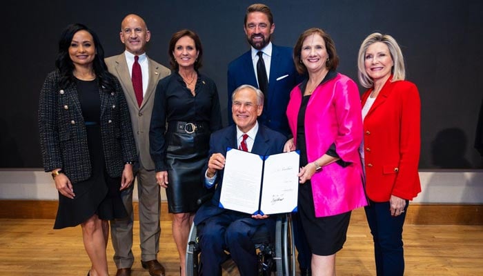 Texas Governor Greg Abbott shows off House Bill 4211 after he signed it into law. — Reporter