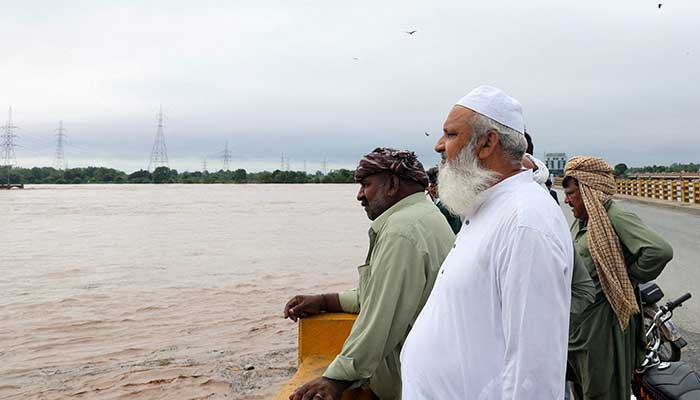 Men stand on a bridge over the Chenab River, following the monsoon rains and rising water level in Wazirabad, in Punjab on August 27, 2025. — Reuters