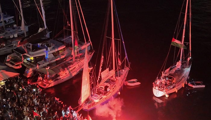 A screenshot from a drone video shows people lighting flares at the port of Ermoupolis during the departure of two sailing boats, Electra and Oxygen, part of the Global Sumud Flotilla aiming to reach Gaza and break Israels naval blockade, on Syros island, Greece, September 14, 2025. — Reuters