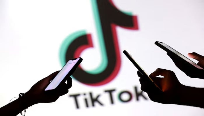 Teenagers pose for a photo while holding smartphones in front of a TikTok logo in this illustration taken September 11, 2025. —Reuters
