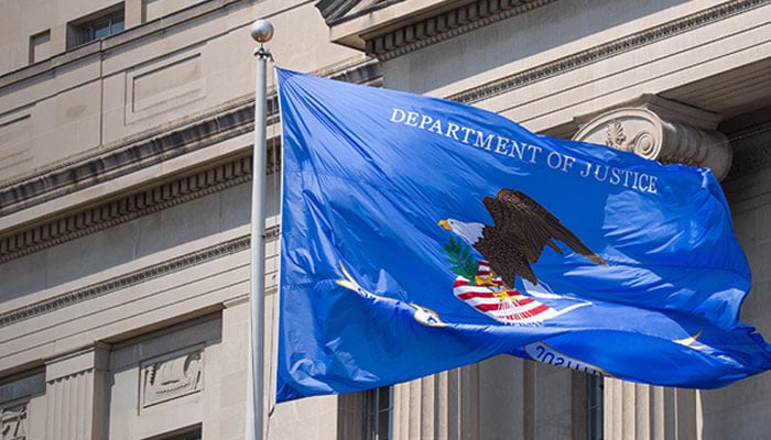 The image shows the flag of Department of Justice fluttering at its building. — DOJ/File