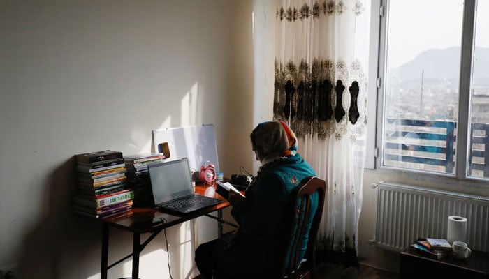 Sana, an Afghan teacher, reads a book before starting an online class, at her house in Kabul, Afghanistan, February 28, 2023. — Reuters