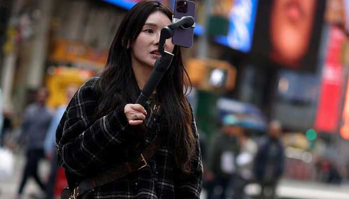 A woman makes a video with a mobile phone to post on TikTok as she stands in Times Square in New York City, New York, US, March 13, 2024. — Reuters