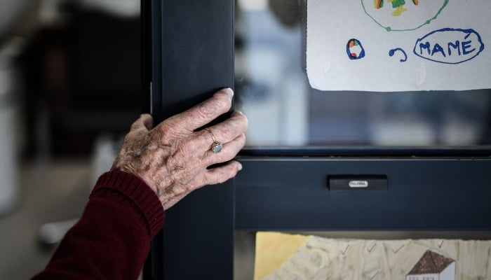 In this picture taken on September 9, 2020 an Alzheimers patient stands at the entrance of the hairdressing salon of the village Landais Alzheimer site for Alzheimers patients in Dax, southwestern France. — AFP