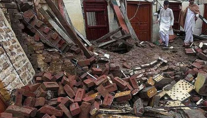 This representative image shows two people inspecting a collapsed roof. — Radio Pakistan/File