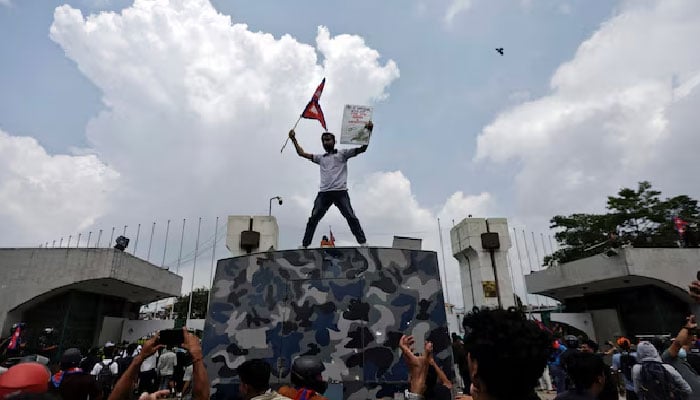 A demonstrator waves a flag as he stands atop a vehicle near the entrance of the Parliament during a protest against corruption and government’s decision to block several social media platforms, in Kathmandu, Nepal September 8, 2025. — Reuters