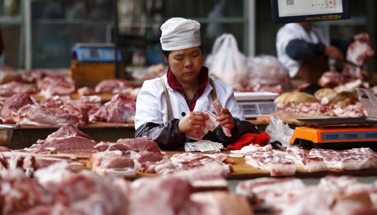 A woman in China counts days income at a meat shop. — Reuters/File