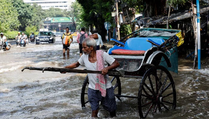 A man wades through a waterlogged road with his hand-pulled rickshaw after heavy rainfall in Kolkata, India September 24, 2025.