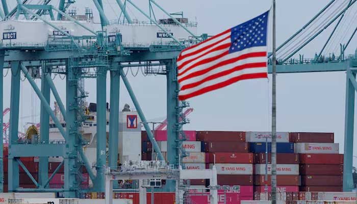 A US flag flutters near shipping containers as a ship is unloaded at the Port of Los Angeles, in San Pedro, California, US on May 1, 2025. — Reuters