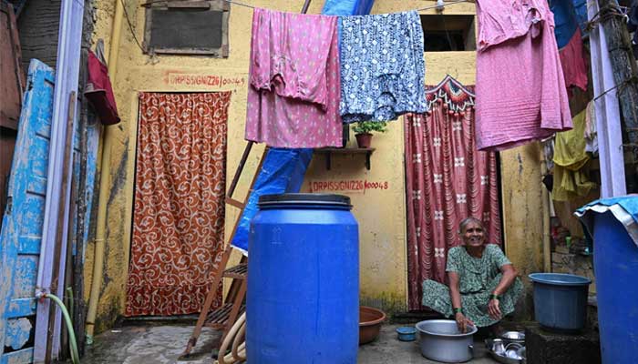 This image shows a resident, eligible for relocation under an urban renewal project, washing utensils outside her house marked for redevelopment in Dharavi, a slum settlement in Mumbai, India on July 9, 2025.