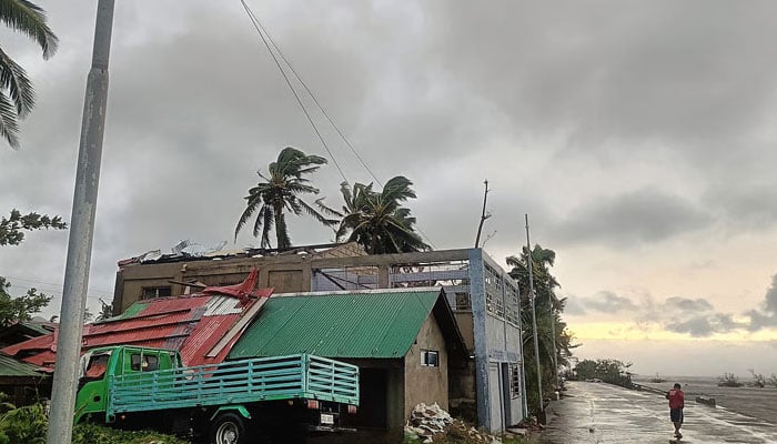 This handout photo taken September 26, 2025 and received through the courtesy of Facebook page of Engineer Jerome Martinez, shows a resident walking past a building with ripped roof destroyed at the height of Severe Tropical Storm (STS) Bualoi, in Masbate City, Bicol region, south of Manila. — AFP