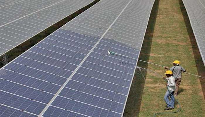 Two workers clean off dust accumulated on solar panels. — SSEP website/File