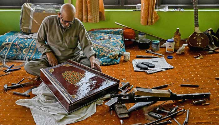 Artisan Ghulam Mohammad Zaz makes the Santoor instrument at his home in Srinagar, IIOJK on September 23, 2025. — AFP