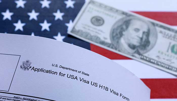 US flag, mock passport, 100 dollar banknote and H-1B visa application form are seen in this illustration taken September 26, 2025. — Reuters