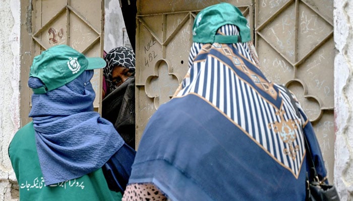 Health workers speak with a woman (Centre) in Karachi on September 24, 2025, during a door-to-door human papillomavirus (HPV) vaccination drive against cervical cancer. — AFP