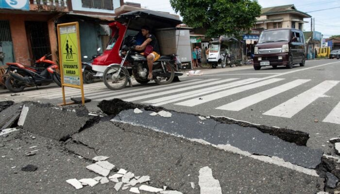 Vehicles manoeuvre past a damaged part of a road in Bogo City on October 1, 2025. — AFP