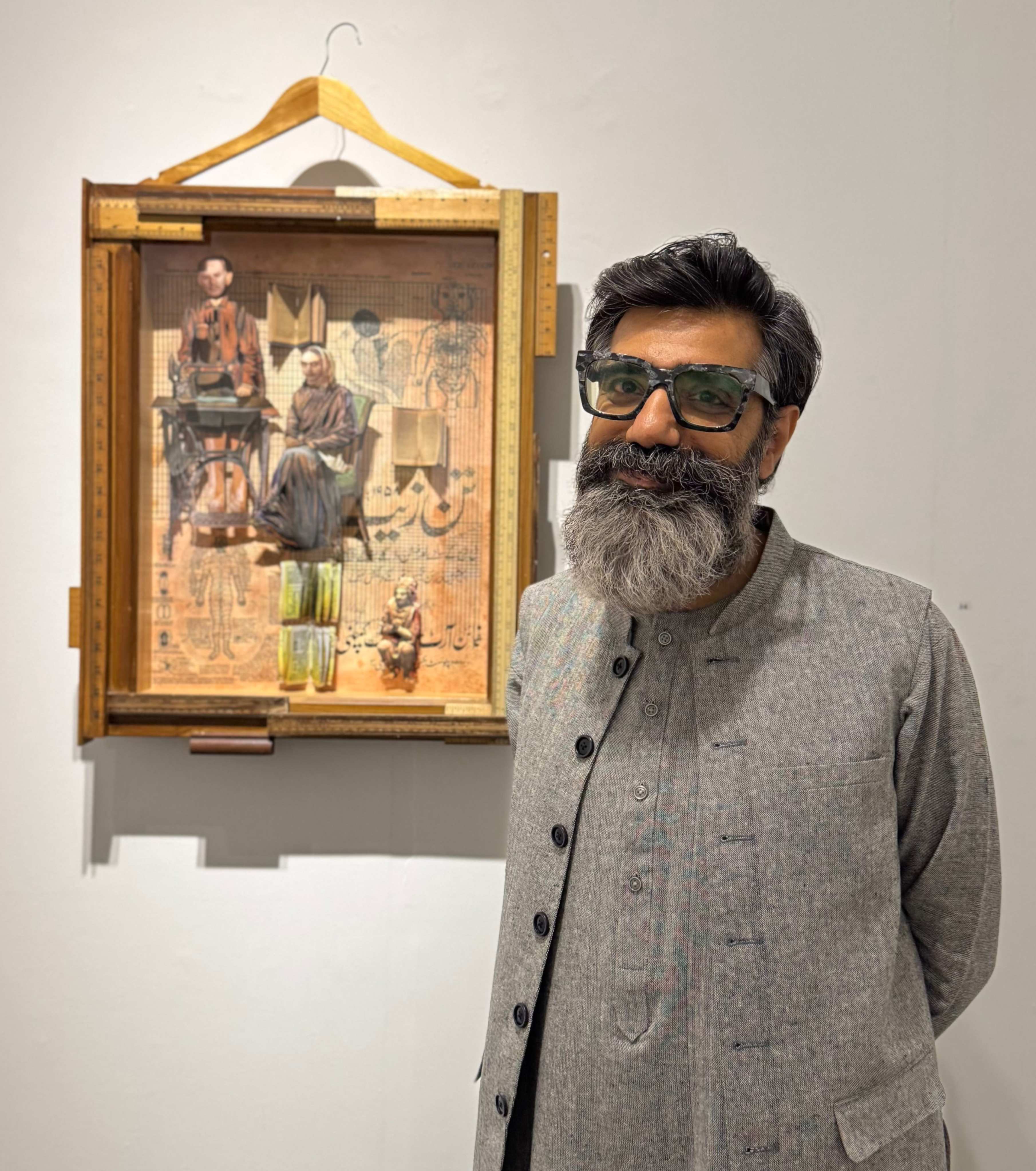 Mohsin Shafi poses alongside his artwork Tan Zaib. — Photo by author