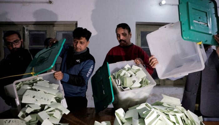 This undated image shows election workers emptying ballot boxes after polls closed at a station during the general election in Lahore. — Reuters