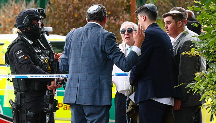 Armed police officers talk with members of the community near Heaton Park Hebrew Congregation synagogue in Crumpsall, north Manchester, on October 2, 2025, following an incident at the synagogue. — AFP