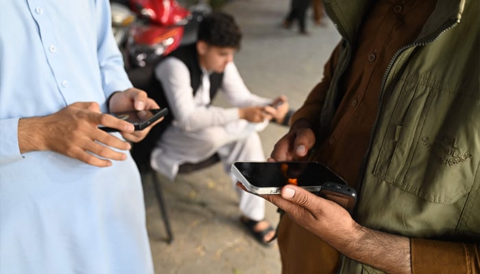 Afghan men use their mobile phones in Kabul on October 1, 2025. Mobile networks and the internet were restored across Afghanistan on October 1, 48 hours after the Taliban authorities shut down telecommunications. — AFP
