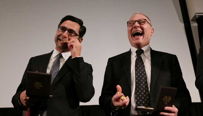 David Card (right) laughs at a joke in this file image. — AFP