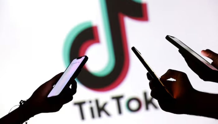 Teenagers pose for a photo while holding smartphones in front of a TikTok logo in this illustration taken September 11, 2025. — Reuters