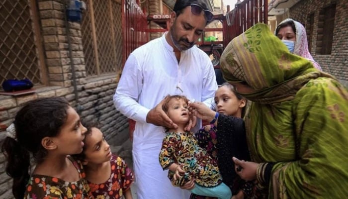 A health worker administers polio drops to a child during a door-to-door vaccination campaign in Peshawar on September 12, 2024. — AFP