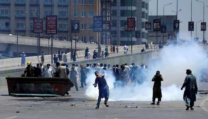 Supporters of PTI founder Imran Khan throw stones towards police during a protest against Khans arrest, in Peshawar on May 10, 2023. — Reuters