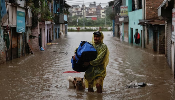 A man carries a bag as he wades through a flooded street along the bank of overflowing Bagmati River following heavy rains, in Kathmandu, Nepal, October 4, 2025. — Reuters