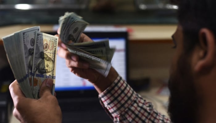 A Pakistani dealer counts US dollars at a currency exchange shop in Karachi. — AFP/File