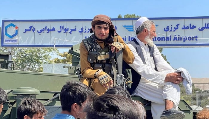 A member of Taliban forces (L) sits on an armoured vehicle outside Hamid Karzai International Airport in Kabul, Afghanistan. Reuters/File
