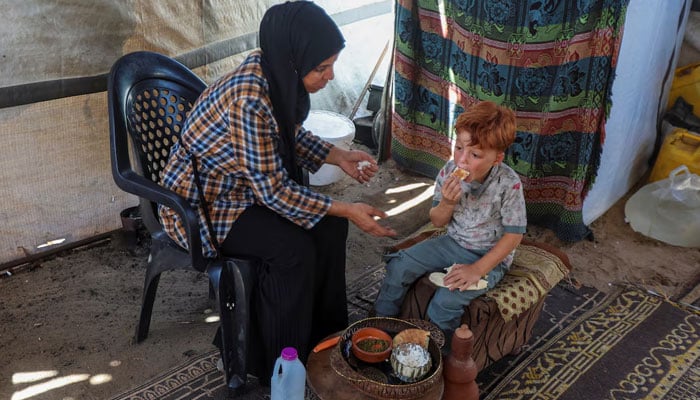 Palestinian woman Inas Abu Maamar, who was photographed at Nasser hospital morgue on October 17, 2023, cradling the body of her five-year-old niece Saly, helps feed her nephew Ahmed, Salys brother, at their tent where they shelter after being displaced from their home, in Khan Younis in the southern Gaza Strip July 30, 2025. Ahmed lost his two sisters, Saly and Seba, his parents, maternal grandparents and paternal grandfather in Israeli attacks during the war.— Reuters