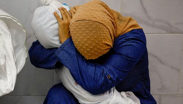 Palestinian woman Inas Abu Maamar, 36, embraces the body of her 5-year-old niece Saly, who was killed in an Israeli strike, at Nasser hospital in Khan Younis in the southern Gaza Strip, October 17, 2023. — Reuters
