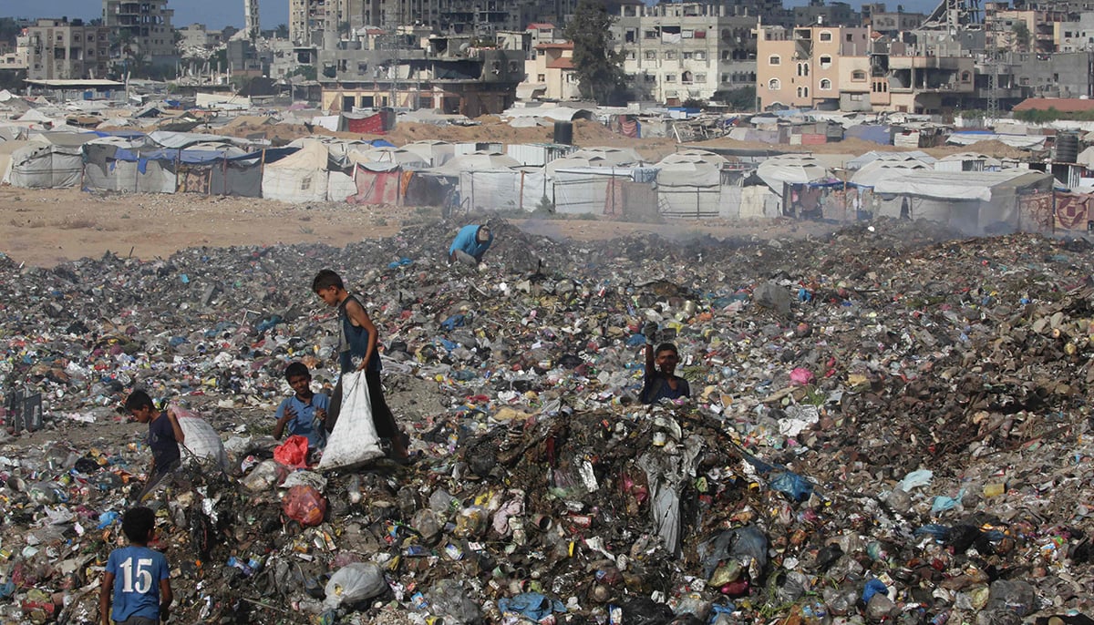 Displaced Palestinian children search of items that could be used as fuel for cooking amid a pile of garbage next to destroyed buildings at the Bureij camp for refugees in the central Gaza Strip on October 6, 2025. — AFP