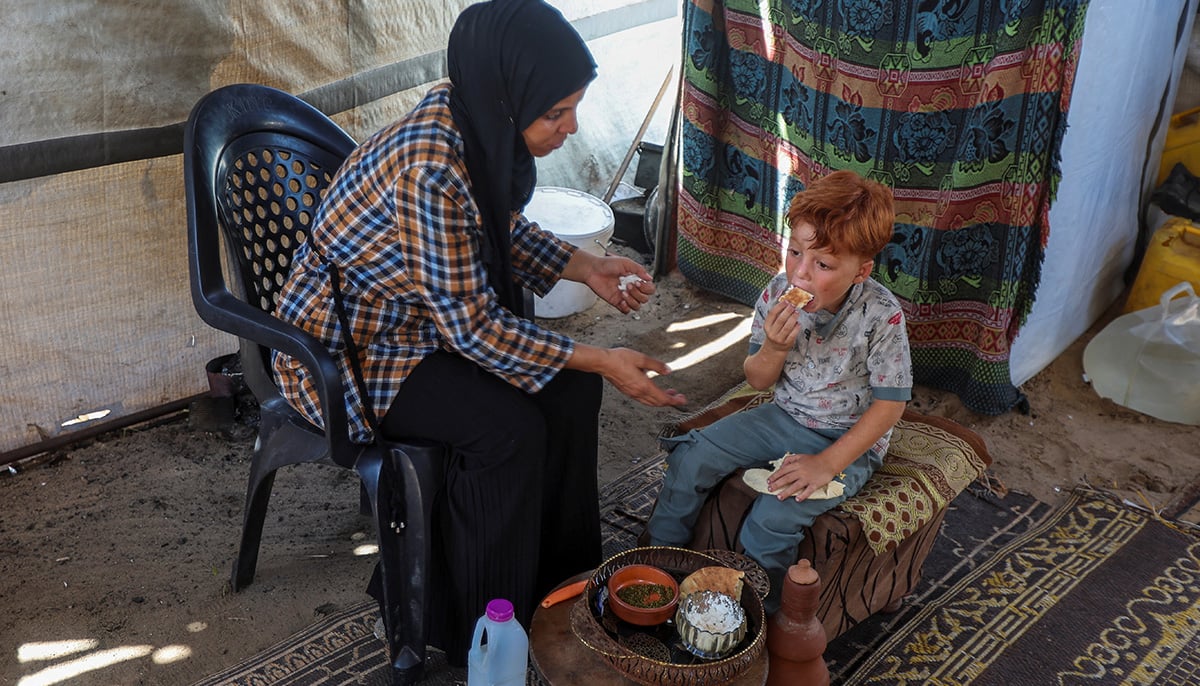 Palestinian woman Inas Abu Maamar, who was photographed at Nasser hospital morgue on October 17, 2023, cradling the body of her five-year-old niece Saly, helps feed her nephew Ahmed, Salys brother, at their tent where they shelter after being displaced from their home, in Khan Younis in the southern Gaza Strip, July 30, 2025. Ahmed lost his two sisters, Saly and Seba, his parents, maternal grandparents and paternal grandfather in Israeli attacks during the war. — Reuters