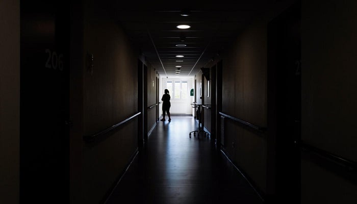 A silhouette of a woman stands at the end of a dark corridor, reflecting the isolation and heaviness often felt in depression. —AFP/File