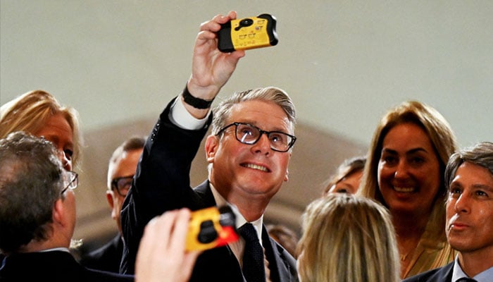 British Prime Minister Keir Starmer takes a selfie with a disposable camera during an interaction with business leaders at the Taj Mahal Palace in Mumbai, India, October 8, 2025. — Reuters