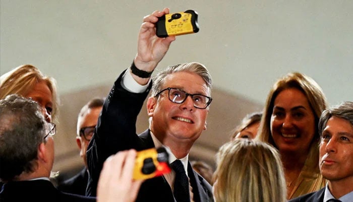 British Prime Minister Keir Starmer takes a selfie with a disposable camera during an interaction with business leaders at the Taj Mahal Palace in Mumbai, India, October 8, 2025. — Reuters