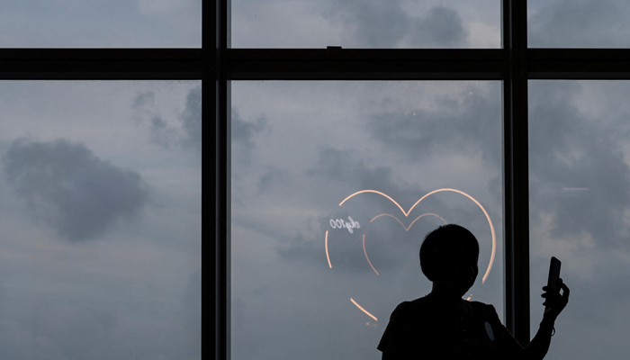 A woman takes a photo in front of heart-shaped light installations. — Reuters