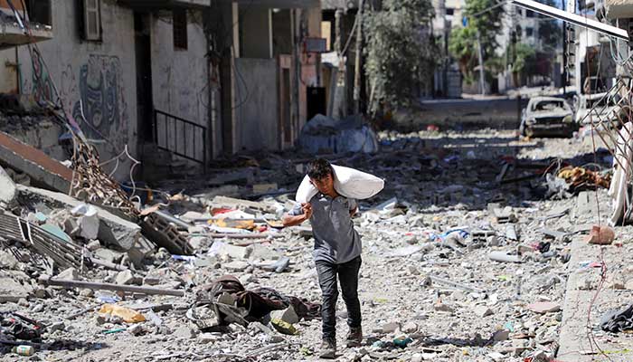 Palestinian boy carries a bag with flour at Sabra neighbourhood, following Israeli operation, in Gaza City, October 8, 2025. — Reuters
