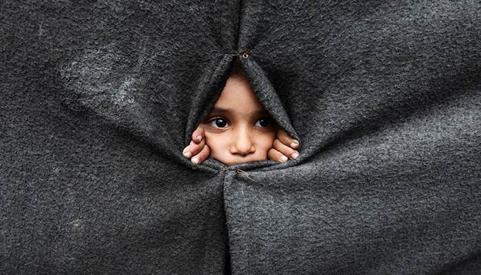 A displaced Palestinian child looks through a covering made from blankets as they take shelter at an UNRWA-run school in Khan Younis in the southern Gaza Strip, October 9, 2025. — Reuters
