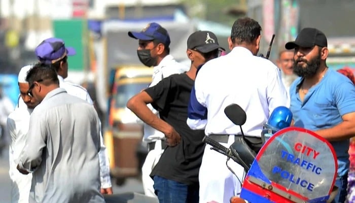 Traffic police officials charge a challan for violating the traffic rules at Saddar area in Karachi on Tuesday, April 15, 2025. — PPI
