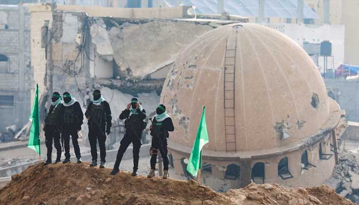 Hamas fighters stand guard during a handover of deceased hostages, in the southern Gaza Strip, February 2025. — Reuters