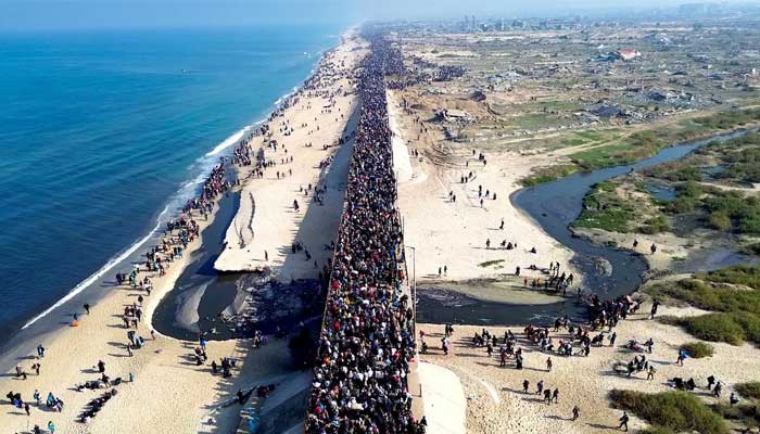 Palestinians cross the desiccated Wadi Gaza as they return home to northern Gaza. — AFP