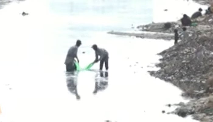 People can be seen trying to find gold particles from the Malir River in Karachi on October 11, 2025. — YouTube/Geo News/screengrab